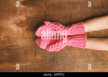 Mani ragazza vestita in rosa guanti sotto lo sfondo di legno. Copia dello spazio. Divulgato palms Foto Stock