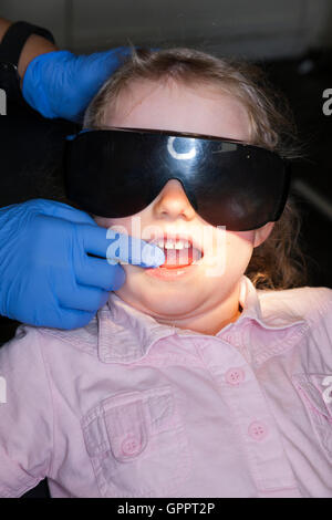 Ragazza 4 anni 4 anno di età bambino indossare occhiali di protezione durante il check up @ dentista per bambini / bambini pratica dentale Foto Stock