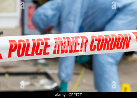 La polizia di cordone interno il nastro di barriera e una scena del crimine officer / ufficiali, & identificazione di prove marcatore numero / marcatori. Regno Unito Foto Stock