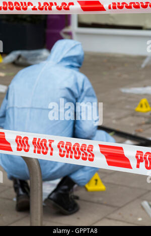 La polizia non superano la barriera di nastro & scena del crimine officer / crimini ufficiali, prove & numero di identificazione dei marcatori marcatore. Regno Unito Foto Stock