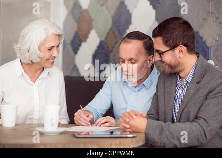 Piacevole uomo senior carte di firma Foto Stock