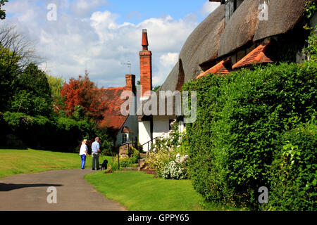 Dog walkers passare un mezzo in legno cottage in Boar Lane, Welford-on-Avon Warwickshire. Foto Stock