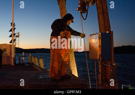 Un pescatore scarica la sua barca al Dock di città su una sera d'inverno in Bar Harbor, Maine. Foto Stock