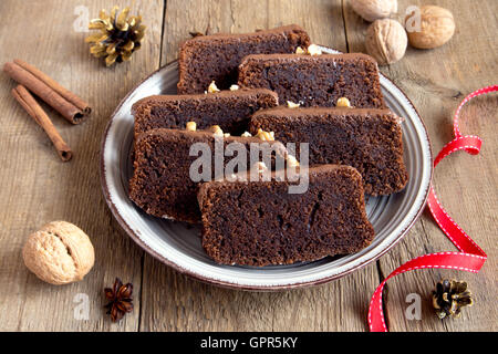 Cioccolato torta a fette con i dadi e le spezie per il Natale su rustico sfondo di legno Foto Stock