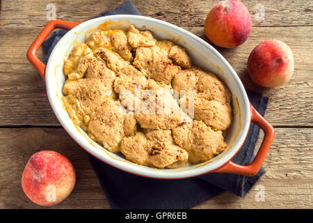 In casa peach cobbler (crumble) in una teglia sopra rustico sfondo di legno Foto Stock