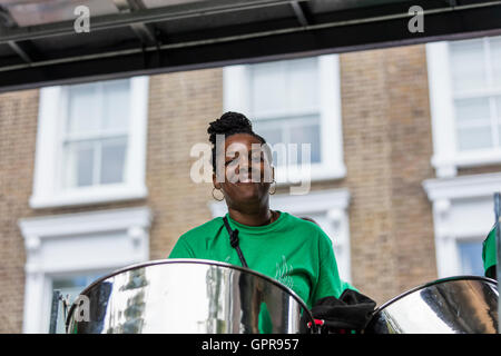 Il nero dei Caraibi donna in verde T shirt giocando i fusti di acciaio in un nastro di acciaio su un autocarro in corrispondenza del carnevale di Notting Hill Foto Stock