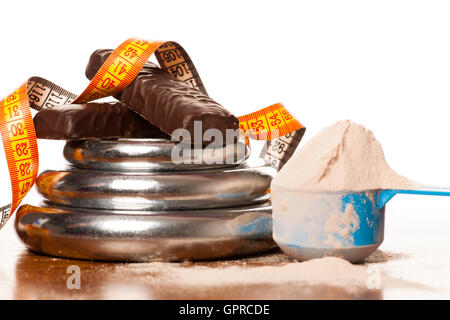 La proteina del siero di latte in polvere nel misurino, proteina bar, il metro a nastro e il manubrio su sfondo di legno. Foto Stock