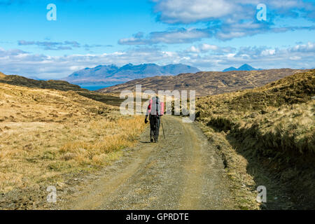 Walker sulla via da Harris Bay voce a Kinloch, Isola di Rum, Scotland, Regno Unito. Il Cuillin Hills di Skye in distanza. Foto Stock