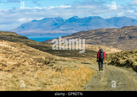 Walker sulla via da Harris Bay voce a Kinloch, Isola di Rum, Scotland, Regno Unito. Il Cuillin Hills di Skye in distanza. Foto Stock