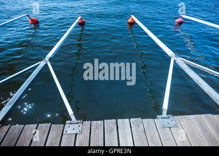 Red boe di ormeggio in una fila galleggiante sull'acqua blu, marina attrezzature portuali. Spazio vacante per yacht e barche Foto Stock