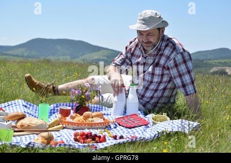 L'uomo su ricco picnic sulla giornata di sole con le colline di Zlatibor Mountain in background Foto Stock