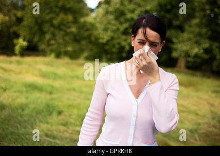 Giovane donna che soffre di un freddo soffia il naso Foto Stock