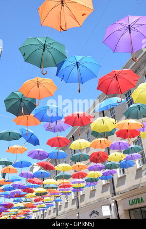 Multi-ombrelloni colorati contro il cielo blu su una strada Foto Stock