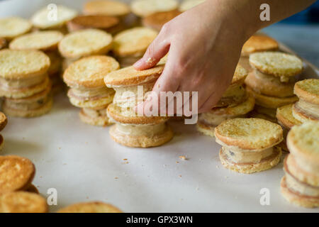 Mano trattiene biscotti frollini con crema. Foto Stock