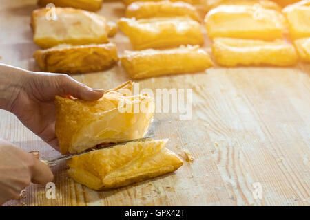 Mano con coltello taglia pasta frolla. Foto Stock