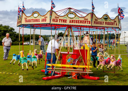 I bambini a cavallo su un tradizionale giostra (merry-go-round), annuale Hartfield Village Fete, Hartfield, East Sussex, Regno Unito Foto Stock