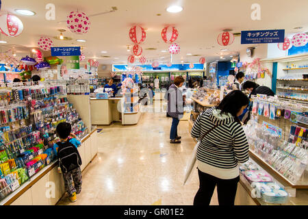 Interno del negozio di articoli da regalo a Osaka, Acquario Kaiyukan. Vista lungo due espositori con vari souvenir e le donne giapponesi e un bambino guardando. Foto Stock