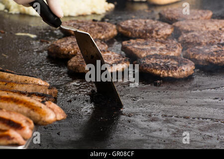 Gli hamburger e salsicce essendo cotti su una azionato a gas piastra su agosto 20th, 2016 a Portrush , Irlanda del Nord Foto Stock