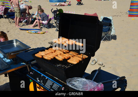 Salsicce cottura su barbecue a gas ad Oriente Strand spiaggia Portrush, Irlanda del Nord, ci sono alcune persone sconosciute in backgrou Foto Stock