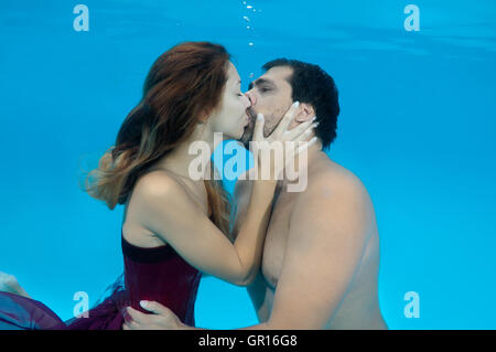 Odessa, piscina, Ucraina. 15 ottobre, 2014. Uomo e donna bellissima con capelli lunghi in un lungo abito rosso baciare sotto acqua, fasihon subacquea in piscina, Odessa, Ucraina © Andrey Nekrasov/ZUMA filo/ZUMAPRESS.com/Alamy Live News Foto Stock