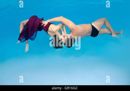 Ottobre 15, 2014 - Odessa, piscina, Ucraina - uomo e donna bellissima con capelli lunghi in un lungo abito rosso baciare sotto acqua, fasihon subacquea in piscina, Odessa, Ucraina (credito Immagine: © Andrey Nekrasov/ZUMA filo/ZUMAPRESS.com) Foto Stock