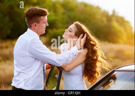 Felice sposa e lo sposo abbracciando vicino auto Foto Stock