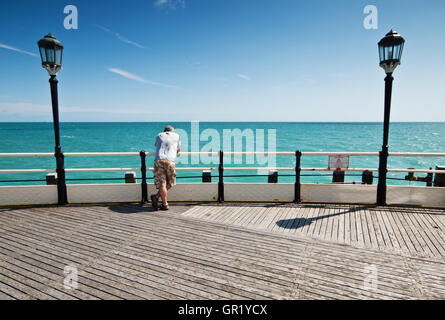 L'uomo contemplando il mare durante una soleggiata giornata estiva in Worthing Pier. Foto Stock