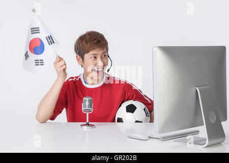 Ritratto di giovane uomo con bandiera coreana e pallone da calcio broadcasting Foto Stock