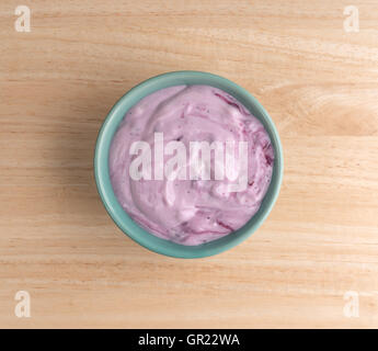 Vista dall'alto di una ciotola con un serving di mirtillo yogurt gourmet su una tavola di legno. Foto Stock