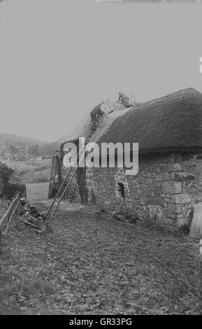 1930s, foto storiche di una thatcher lavorando su un nuovo tetto di paglia su un vecchio edificio agricolo, Chagford, Dartmoor Devon, Inghilterra Foto Stock