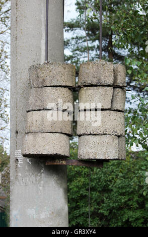 Treno cavi con contrappesi in cemento su un palo vicino alla ferrovia. Foto Stock