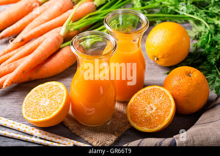 Carota succo di colore arancione su sfondo di legno Foto Stock