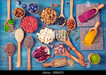 Super Foods in cucchiai e bocce su uno sfondo di legno Foto Stock
