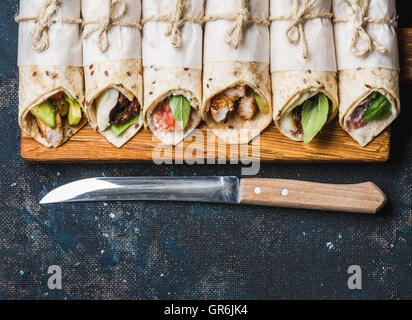 Tortilla avvolge con diversi riempimenti su grigio scuro dello sfondo in calcestruzzo Foto Stock