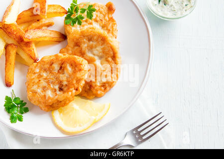 Fatti in casa Torte di pesce con patatine fritte sulla piastra bianca close up Foto Stock