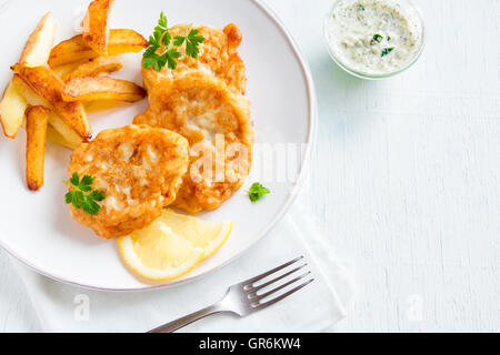 Fatti in casa Torte di pesce con patatine fritte in bianco sullo sfondo di legno con spazio di copia Foto Stock