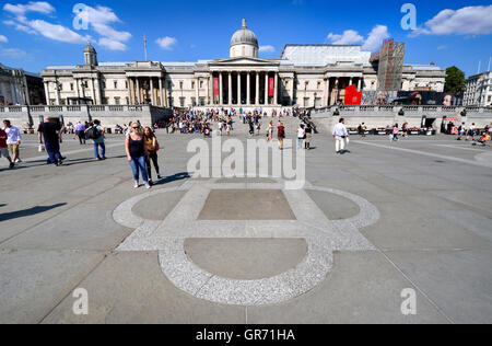 Londra, Inghilterra, Regno Unito. Trafalgar Square. Galleria Nazionale (fondo) e la placca nella pavimentazione con riferimento alle fontane e.. Foto Stock