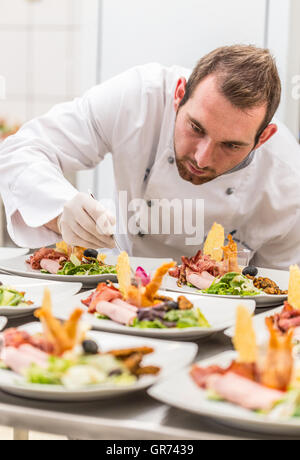 Concentrato chef maschio decorare piatto antipasto in cucina Foto Stock