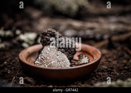 Tartufo nero a fette nel piatto in legno Foto Stock