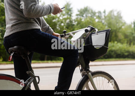 Ritratto di maschio adulto seduto sulla moto con un telefono cellulare Foto Stock