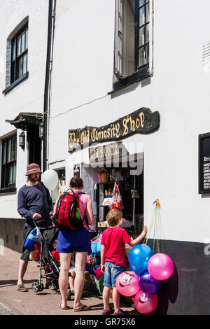 Inghilterra, Broadstairs. Il vecchio negozio di curiosità, famiglia con passeggino e bambino più anziano al di fuori della finestra di vendita acquisto di gelati. Palloncini appeso alla parete. Foto Stock
