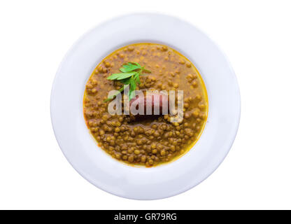 Zuppa di lenticchie in una piastra bianca con salsiccia, isolato su bianco Foto Stock