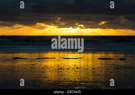 Tempestoso tramonto riflesso in sabbia bagnata, Awakino Beach, Waikato, Isola del nord, Nuova Zelanda Foto Stock