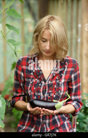 Donna che mantiene un maturo melanzana. Orticoltura, il raccolto, il contadino locale concept Foto Stock