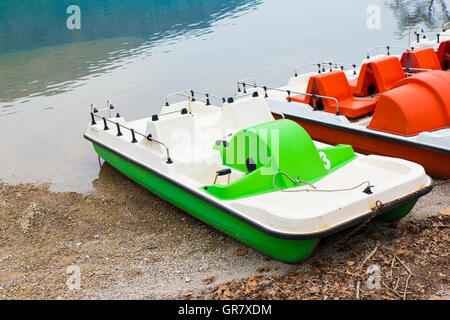 Barche a pedali e abbandonato sulla riva del lago Foto Stock