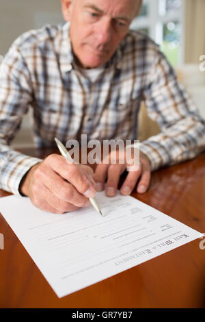 Senior uomo firma Testamento, a casa Foto Stock