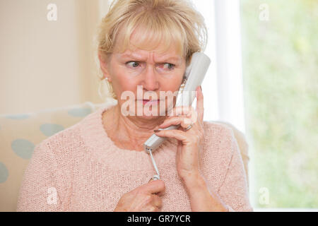 Preoccupato Senior donna rispondendo Telefono in casa Foto Stock