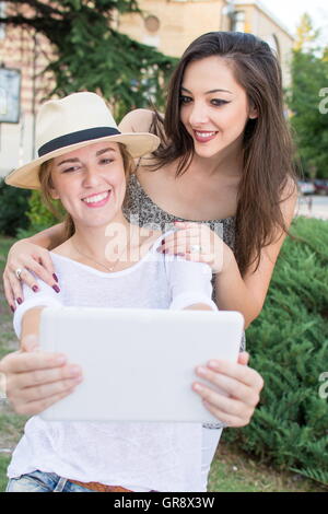 Due amiche tenendo selfie con una compressa Foto Stock