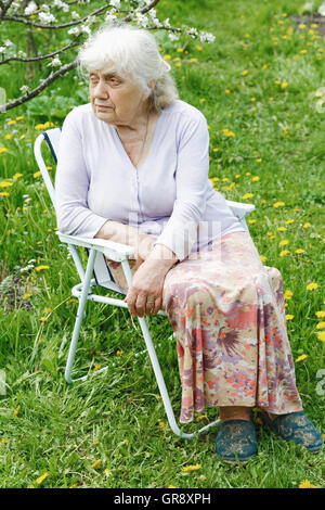 La nonna in giardino sotto una fioritura del melo Foto Stock