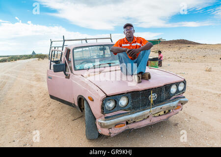 Giovane africano seduto su una vecchia auto Foto Stock